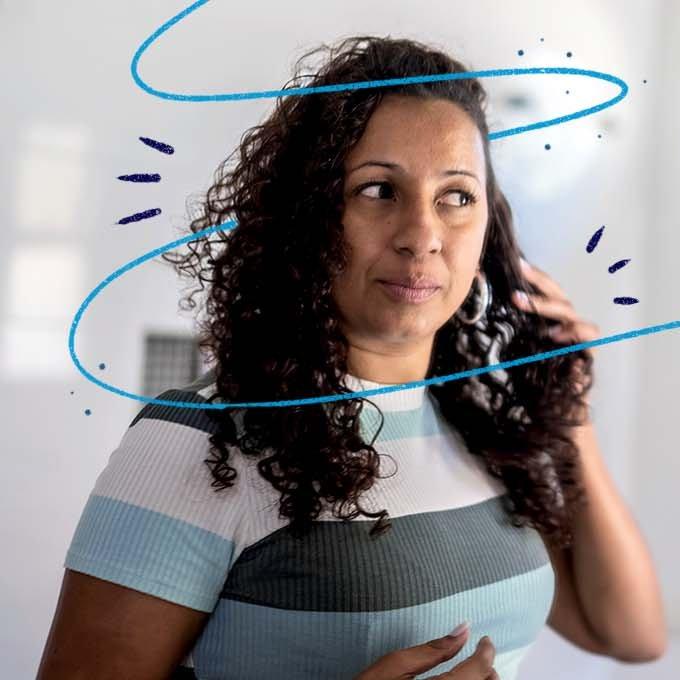 A woman wearing a stripey t-shirt running her hand through her long curly hair